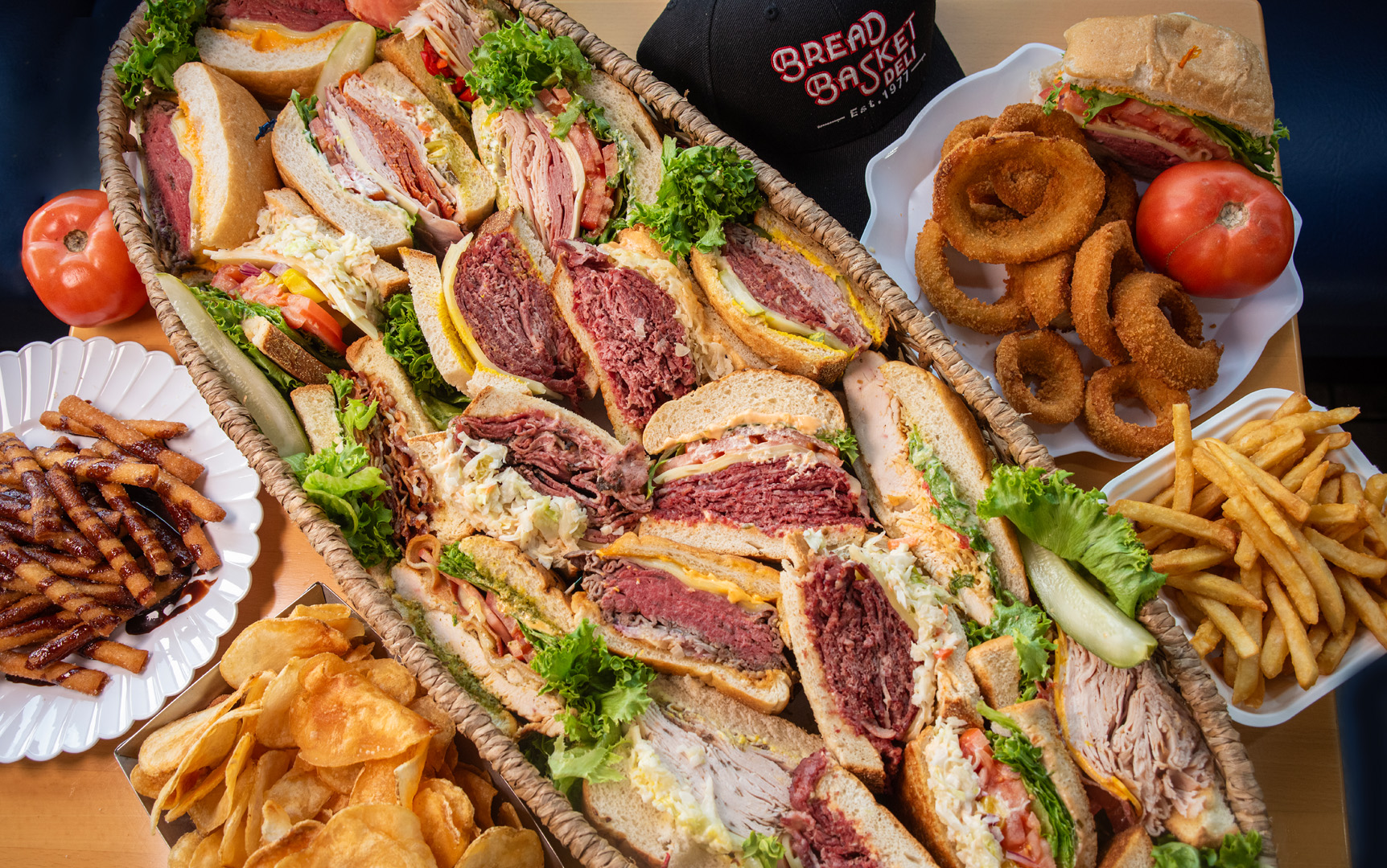 A loaded Bread Basket Deli platter of corned beef, deli sandwiches, onion rings and fries